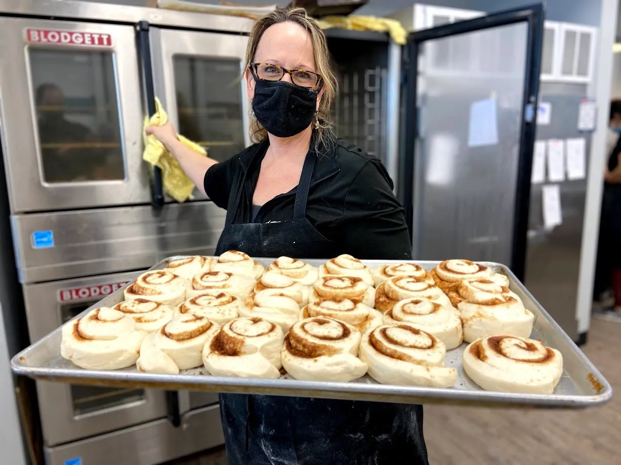 michelle kaiser of the omaha bakery with a fresh tray of cinnamon rolls