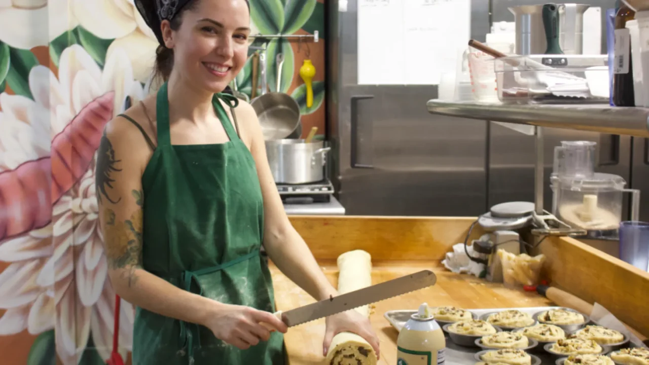 young brunette woman cutting cinnamon roll dough at sugar moon bakery in chicago