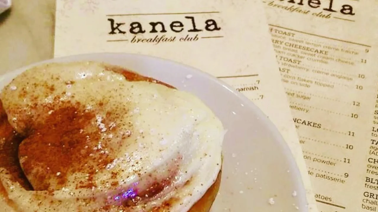 cinnamon roll on a plate next to a kanela breakfast club menu in chicago