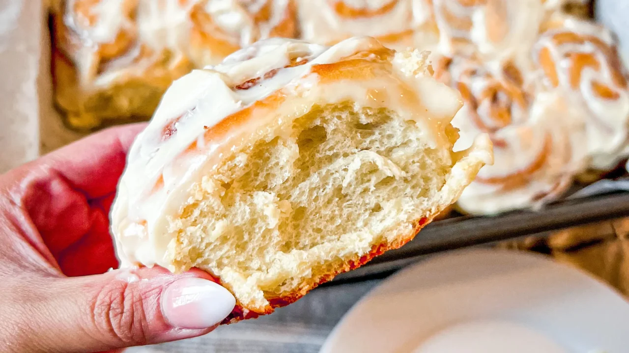 hand holding a freshly baked cinnamon roll