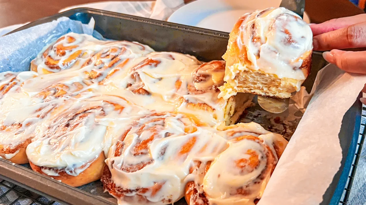 taking cinnamon rolls out of a pan after baking