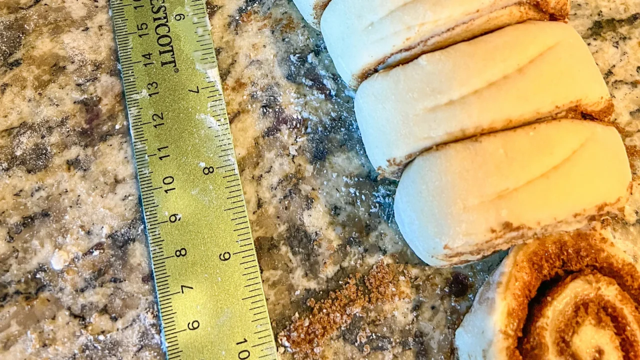 cinnamon rolls cut up with a measuring tape next to them