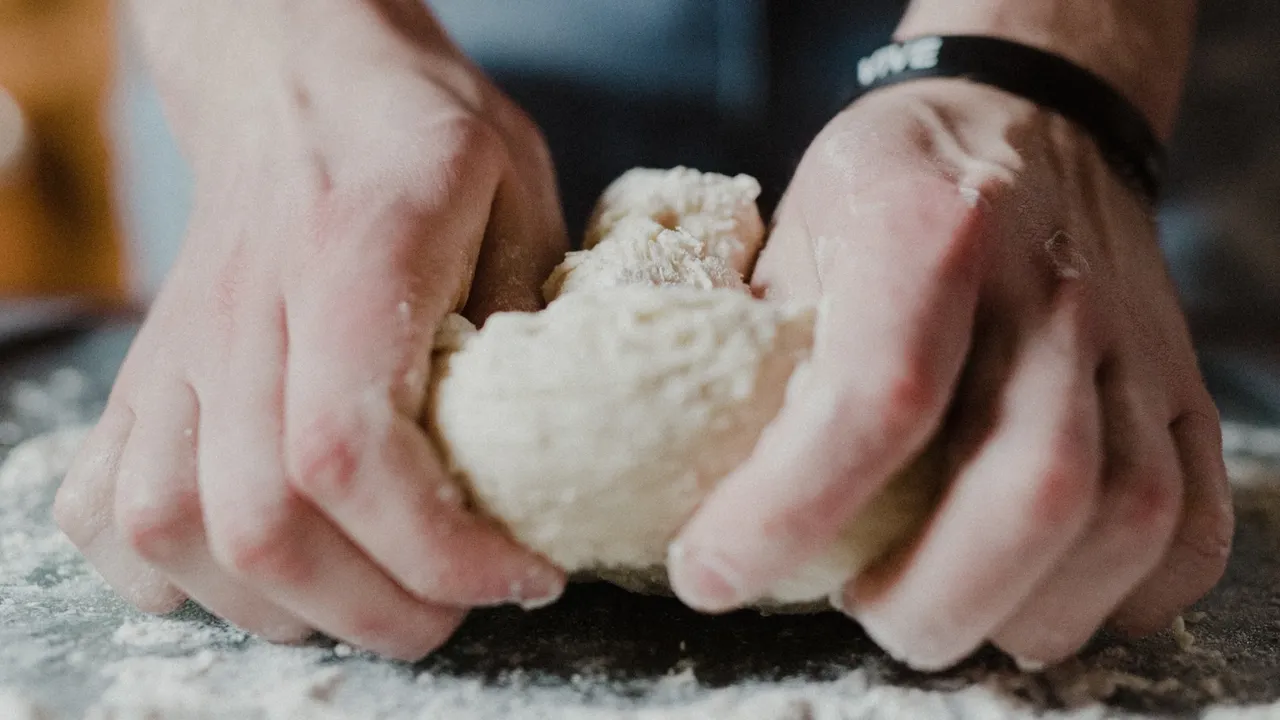 male hands kneeding cinnamon roll dough