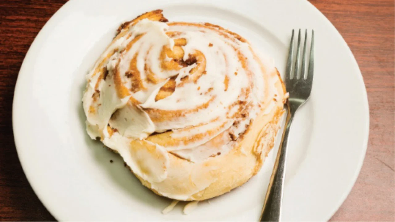 cinnamon roll on a plate with a fork