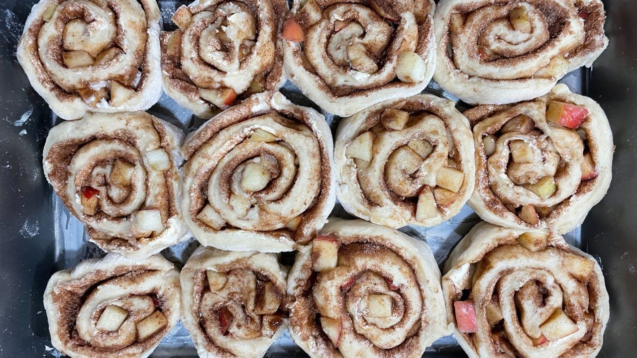 a pan of apple cinnamon rolls with brown sugar maple icing